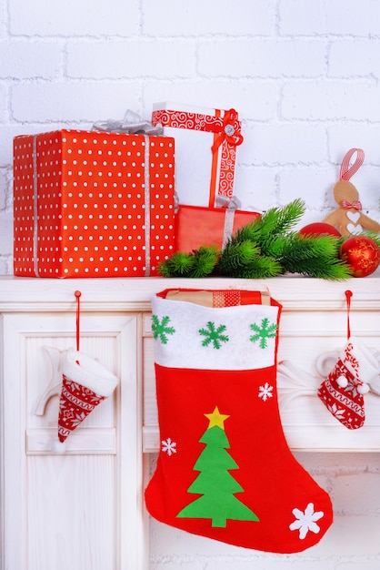 Mantelpiece with gifts and Christmas decoration on brick wall background