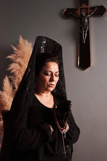 A mantilla woman with her eyes closed while praying with a rosary in her hands