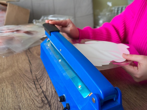 Manual bag sealer for home production, a girl packs finished products with a manual bag sealer