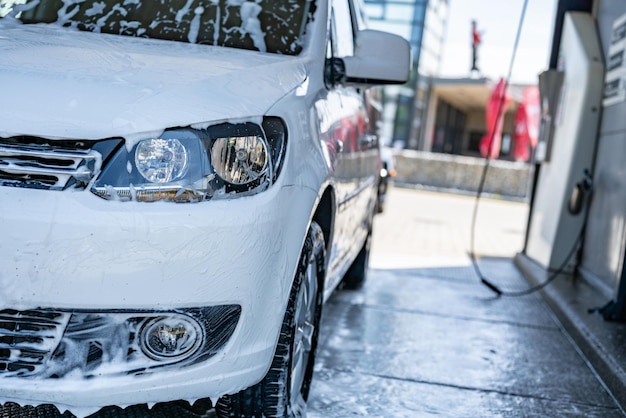 Foto lavaggio manuale dell'auto con schiuma di sapone bianco sul corpo lavaggio dell'auto utilizzando acqua ad alta pressione