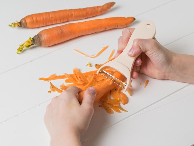 Manual cleaning of carrots with a special tool. Cleaning carrots with a special knife.