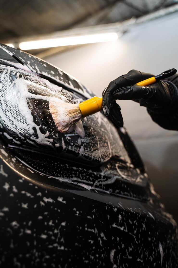 Manual cleaning with soap at self care car wash Cleaning headlights with foam and soft brush Carwash and detailing