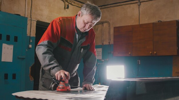 Manual sander sanding a metal detail at the factory, industrial concept