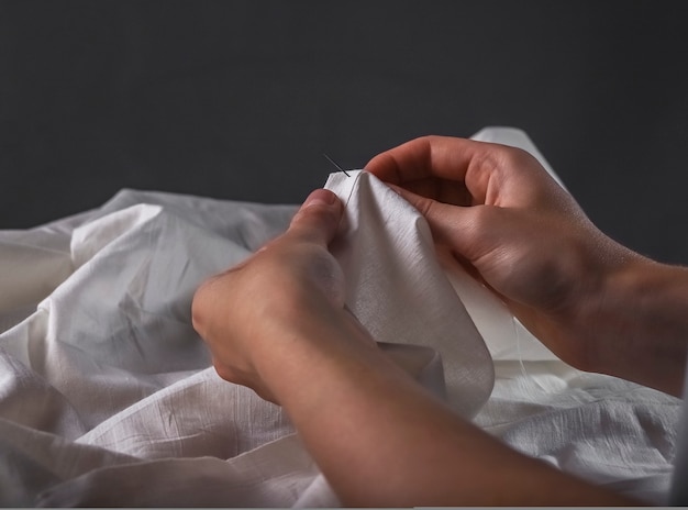 Концепция ручного шитья руками швеи иглой и хлопчатобумажной тканью