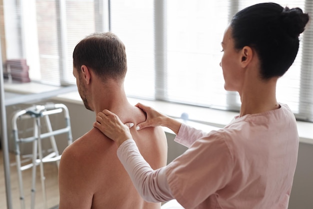 Manual therapist massaging back of patient during medical procedure in hospital