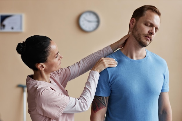 Manual therapist massaging pain neck of patient during physiotherapy in hospital