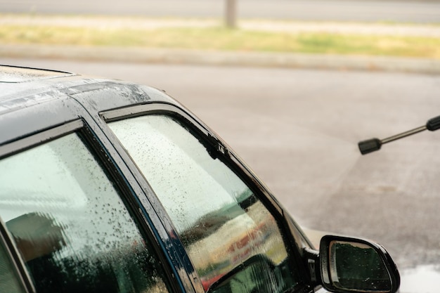 Manual washing of the car with water under pressure on the car wash outside Summer car wash Cleaning the car with highpressure water Washing with soap Close the concept