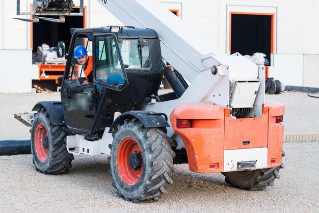 Photo manual worker operating on skid steer loader