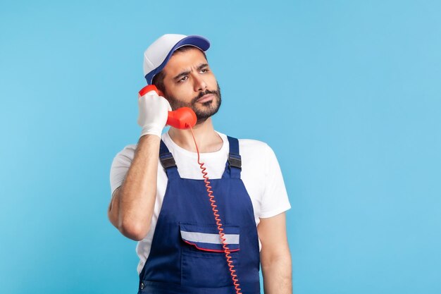 Photo manual worker talking on phone against colored background