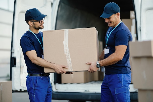 Lavoratori manuali che trasportano una scatola di cartone in un furgone