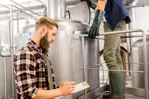 Foto concetto di fabbricazione, attività e persone - uomini con clipboard che lavorano in un birrificio artigianale o in una birreria