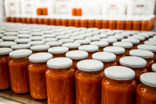 Manufacture of tomato sauce, several glass jars with tomato sauce.