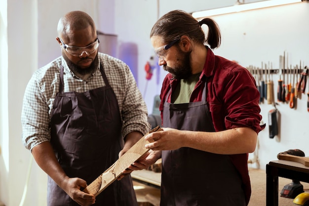 Manufacturer and apprentice analyzing piece of wood together sizing it up