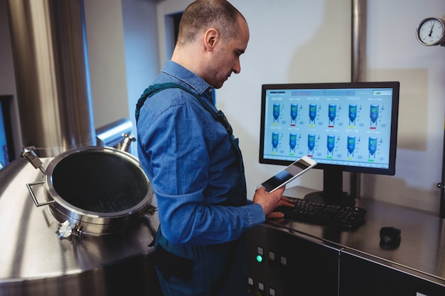 Photo manufacturer holding digital tablet while working on computer