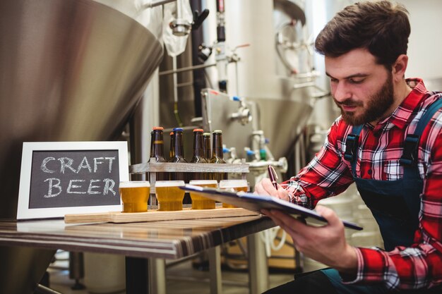 Manufacturer writing on writing pad in brewery