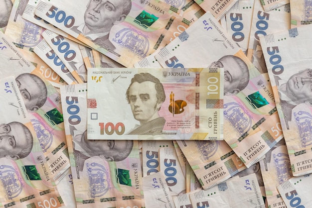 500 Hryvnia 紙幣在平坦的表面上散落,其中的 100 Hryvnya 紙幣是近距離的
