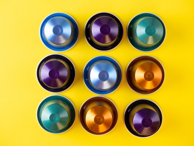 Photo many aluminum coffee capsules are displayed in a row on a yellow background. food pattern. capsules for the coffee machine. top view, flat lay