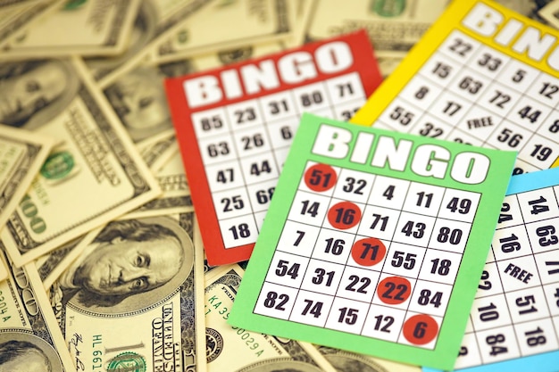 Many bingo boards or playing cards for winning chips and big amount of dollar bills Classic american or canadian five to five bingo cards on money