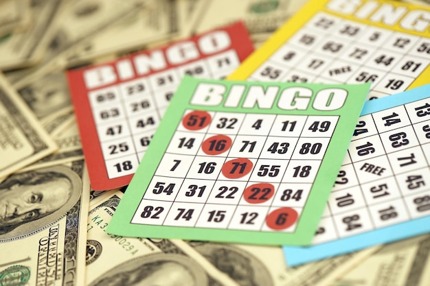 Many bingo boards or playing cards for winning chips and big amount of dollar bills Classic american or canadian five to five bingo cards on money