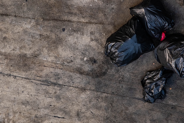 Many black garbage bags that are tied up On the sidewalk