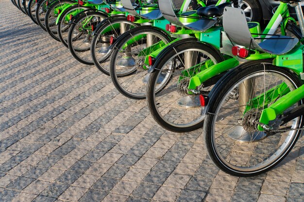 Many black and green bicycles in a row. Trends in bicycle-making industry. Group of cycles. Bike stand on a parking for rent. Eco friendly transportation concept. City eco-friendly transportation