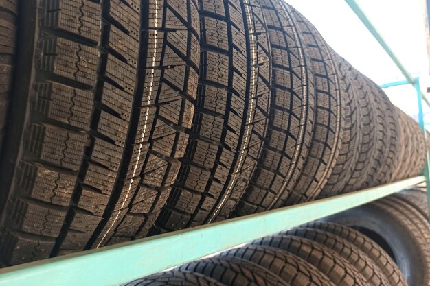 Many black rubber car tires on store shelf for sale.