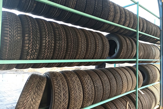 Many black rubber car tires on store shelf for sale.