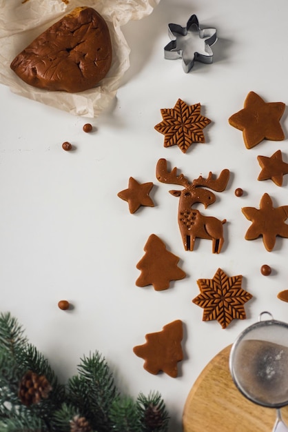 Many blanks of gingerbread cookies of different shapes on a table with christmas decor