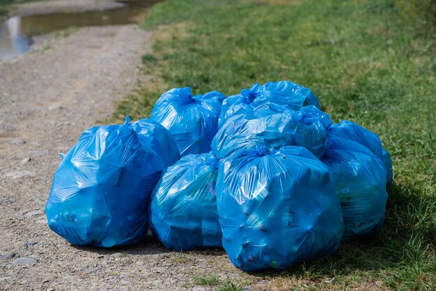 Many blue garbage bags lying on the road on the grass