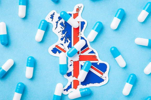 Many blue and white pills capsules on flag of Great Britain