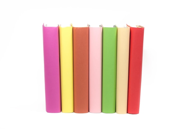 Many books of different colors stand in a row on a white background insulator