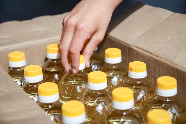 many bottles of sunflower oil in box with people hand background