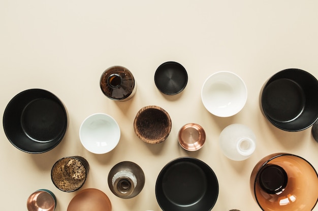 Many bowls, containers, saucers on pastel beige. Flat lay, top view of wooden, ceramic, glass decorations.