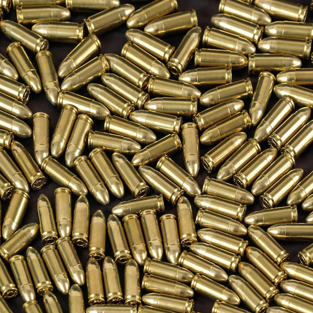 Many brass gun bullets on black table closeup view from above