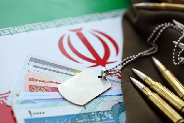 Many bullets and iranian rials money bills on flag of islamic republic of iran