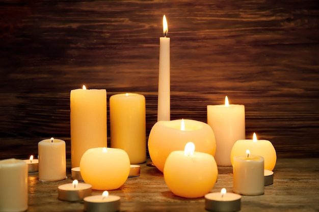 Many burning candles on wooden surface