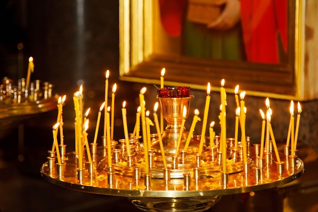 Многие горящие восковые свечи в православной церкви или храме на пасху церемонии