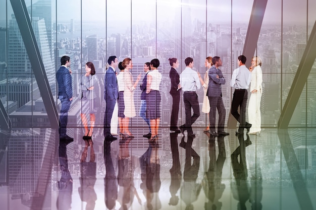 Many business people standing in a line against room with large window looking on city