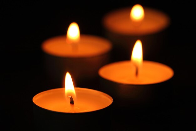 Many candle flames glowing in the dark.