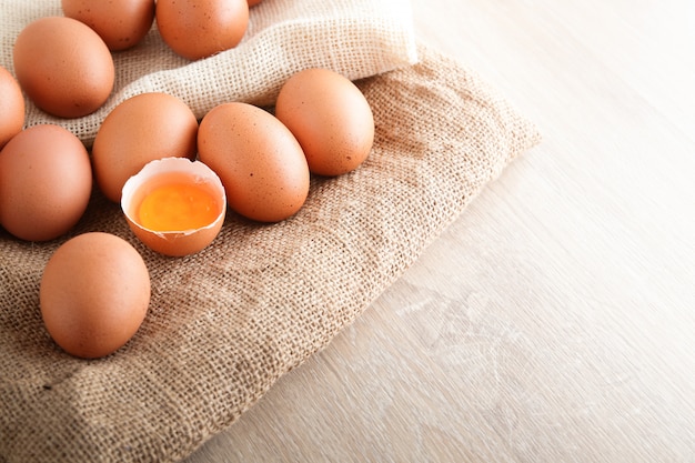 Many chicken eggs are placed on a brown cloth