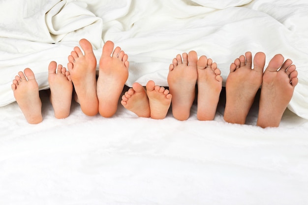 Many children's feet peeking from under the blanket