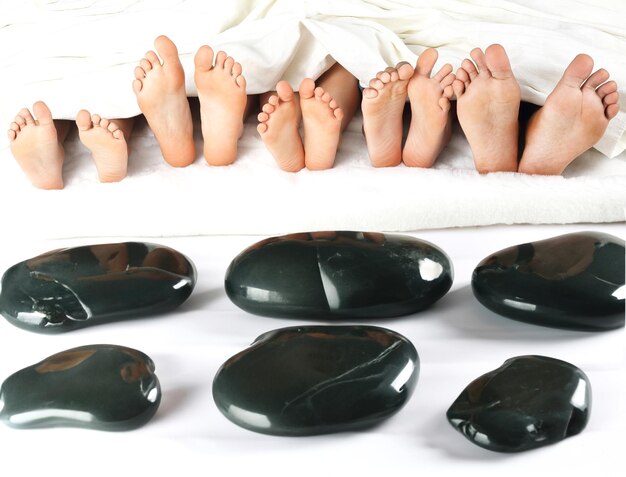 Photo many childrens feet peek out from under the blanket against the background of smooth stones