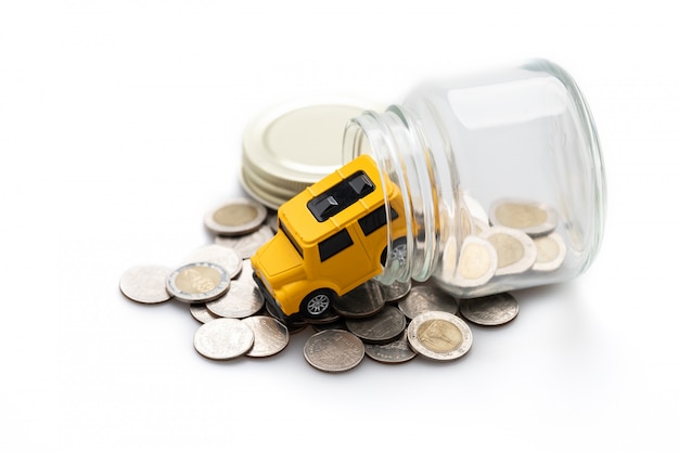 Many coins in a glass jar and a yellow toy car