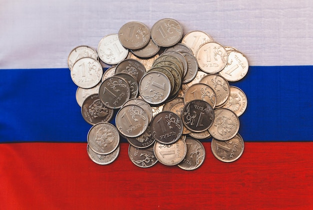 사진 1 루블의 많은 동전이 러시아 돈에 놓여 있습니다.