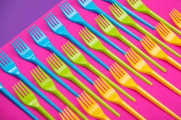 Many color plastic forks on a bright background