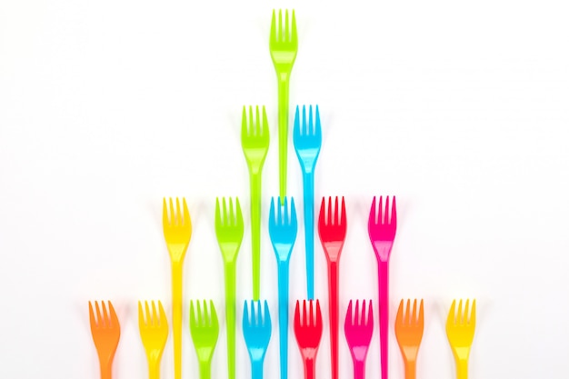 Many color plastic forks on a bright background