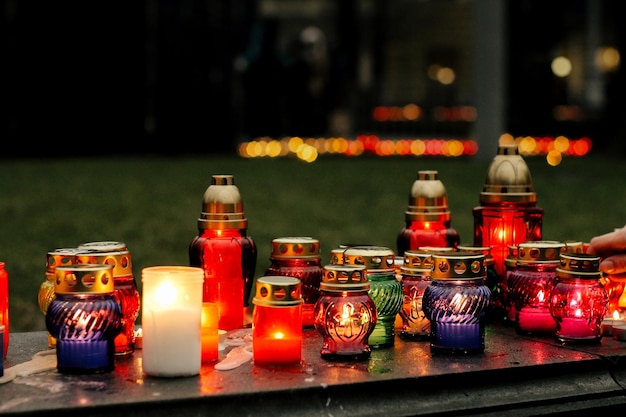 Many colorful candles with light burning in city center on marble stone memorial day and sad bereavement moment