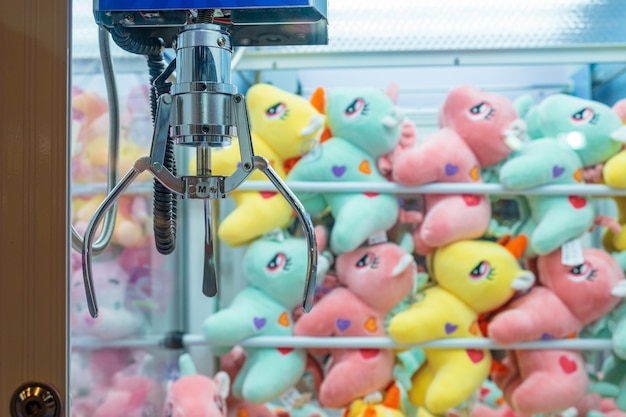 Many colorful dolls put in the cabinet claw game wait for\
people play catching.