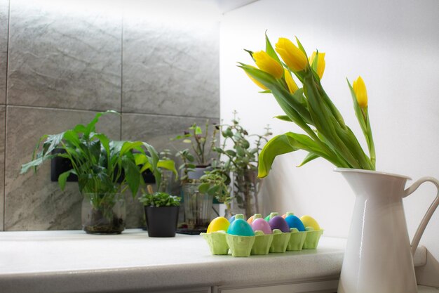 Many colorful easter eggs in carton box on table in kitchen interior