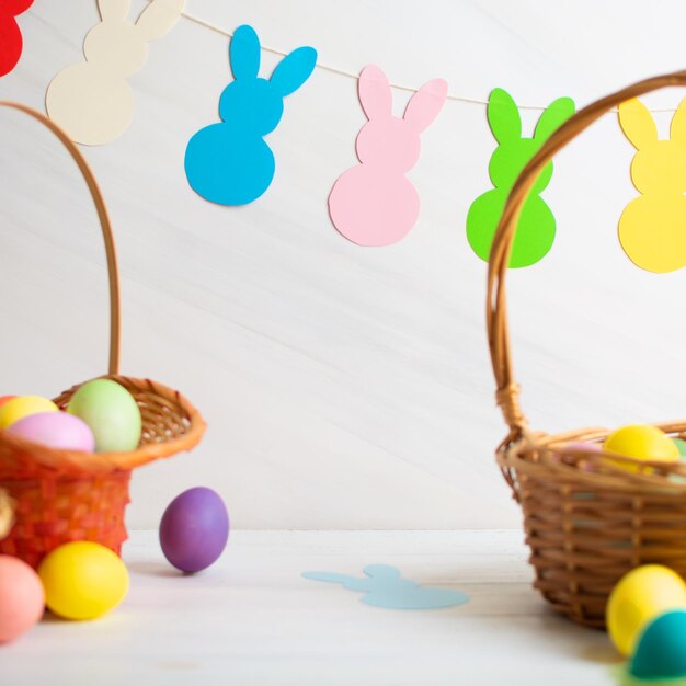 Many colorful easter eggs in wicker basket with paper bunnies garland